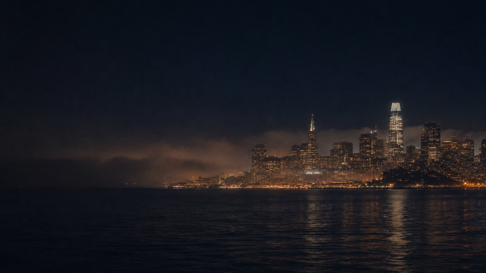 San Francisco skyline at night, fog rolling in over the bay